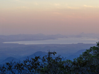 Water Body Amidst Hazy Mountains at Sunset