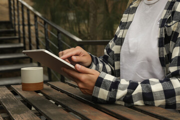 Individual engaged with tablet in calm natural surroundings