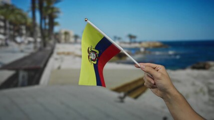 Man holds ecuadorian flag at seaside beach showcasing patriotism against scenic outdoor backdrop. - Powered by Adobe