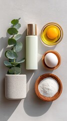 Top View Flat Lay Skincare Bottle Eucalyptus Sprig Egg Yolk Egg White and Rice Grains Arranged on Textured Gray Surface