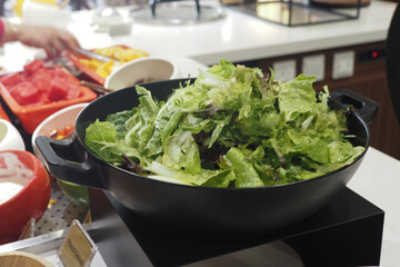 Fresh green salad served in a black bowl on a buffet table