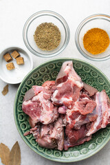 Overhead view of mise en place of ingredients and spices for cooking raw goat meat, top view of chopped goat meat being prepared for cooking