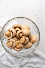 Overhead view of whole button mushrooms in a glass bowl, top view of button mushrooms on white countertop