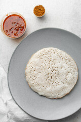 Overhead view of a plate of sinasir and pepper sauce, top view of food from northern nigeria sinasir rice pancake and stew