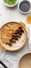 Overhead view of claypot rice with fried tofu and mushrooms in a donabe