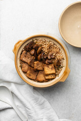 Overhead view of claypot rice with fried tofu and mushrooms in a donabe