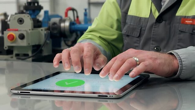  Close Up of an Engineer s Hand Scrolling a Digital Tablet Displaying a Green Checkmark with Machinery in the