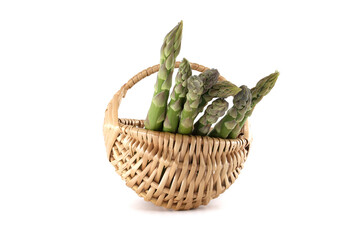 Green asparagus spears elegantly arranged in a woven basket against a white backdrop.