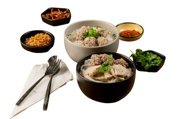 Delicious Vietnamese meal beautifully served with side dishes and cutlery. Bowls of rice noodles and meat with garnishing elements around them.