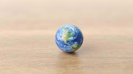 A small globe model representing the Earth against a blurred wooden table background,