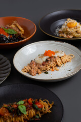 Various Italian pasta on grey background. Spaghetti Aglioeolio, Carbonara, Squid ink, Truffle and Mentaiko.