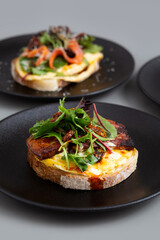 Open Sandwich with Scrambled eggs, Chunk bacon, Salad and Sundry Tomato.