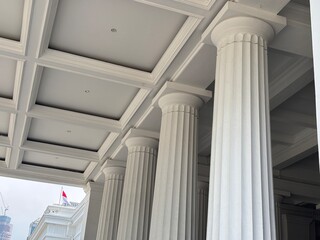 Fototapeta premium low-angle shot of a grand museum entrance or portico featuring a row of tall, fluted white columns and a detailed coffered ceiling.