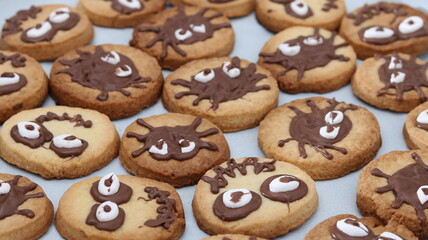 Close-up of Halloween chocolate cookies decorated like spiders with candy eyes and chocolate legs