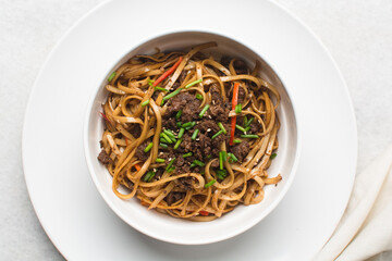 overhead view of fried egg noodles in a white bowl, top view of stir fried noodles in a bowl