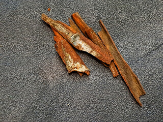Cinnamon sticks displayed against a textured dark grey backdrop, showcasing their rustic, organic