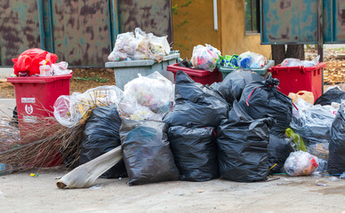Garbage bins and containers full, overflowing, with bags falling on ground in residential area of Bordeaux, France, in a green container.