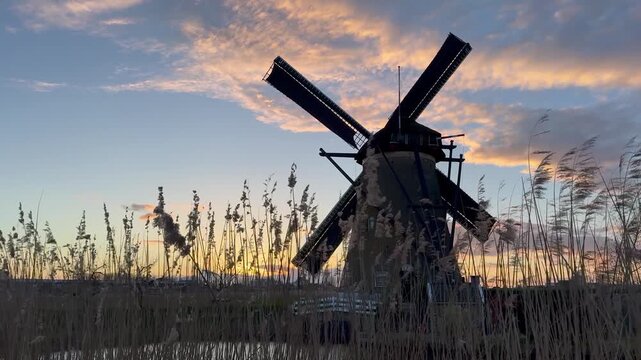 View to the silhouette of Netherlands wooden windmill at sunset in the village of Kinderdijk. The beautiful Dutch canals are filled with water. Unesco World Heritage. Holland, Europe from above.