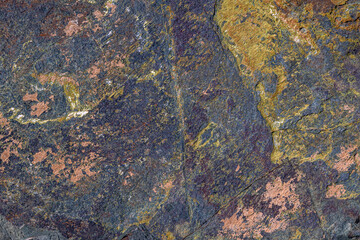 Rough textured rock formation stands prominently in an outdoor natural setting. Daytime light enhances the rugged features and earthy tones of the rock.