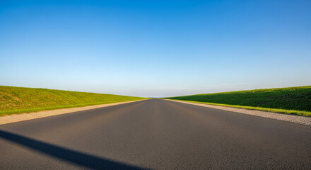 Naklejka premium Empty straight road disappearing into horizon with green grass on sides for concept of journey, future, freedom, and life path
