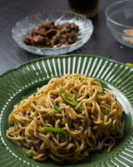 Overhead view of sesame noodles on a green plate, top view of fried ramen noodles with sesame seeds