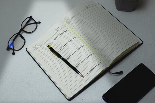 A diary or notebook open on a white desk with the phrase "CHASE OPPORTUNITIES" repeatedly handwritten inside, symbolizing a core investment strategy.