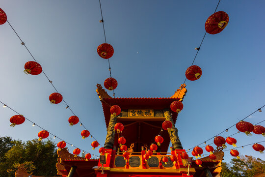 Rows of red and gold paper lanterns hanging in temple - Powered by Adobe