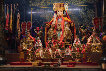 Fototapeta premium Golden chinese deity surrounded by smaller deities in a shrine