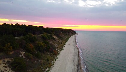 Coastal cliff and sandy beach at colorful sunset