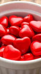 Close-up of a white bowl filled with small, glossy red heart-shaped candies