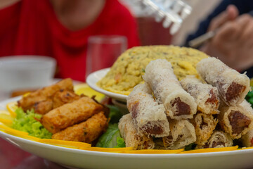 Plate presenting deep fried spring rolls and fried rice being enjoyed by people