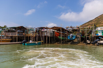 Fishing boats on waterway and floating stilt house at Tai O, a traditional Chinese Fishing Village known as Venice of the Orient, in Hong Kong