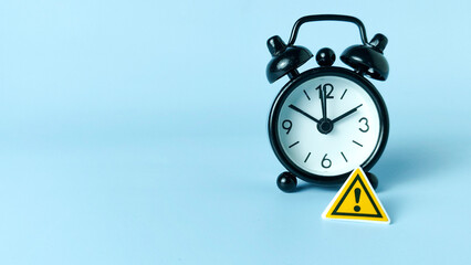 Critical Deadline and Time Management Risk: Warning Sign on a Black Alarm Clock