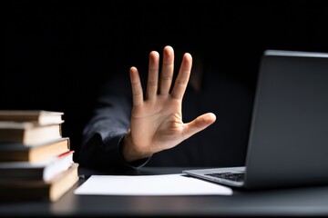 Person at a desk showing open palm gesture, stopping or denying access, protecting privacy and personal information