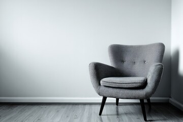 Gray armchair sits in a corner of a minimalist room with light walls.