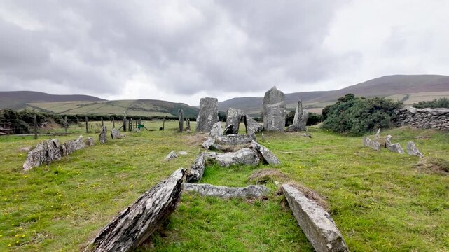 Cashtal yn Ard, a Neolithic chambered tomb, standing in a green field under a cloudy sky. pan right shot