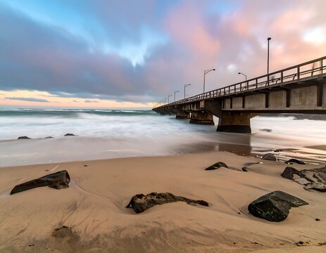 Seaside pier with long exposure water and clouds during colorful sunset