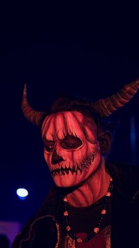 Person in devil pumpkin halloween costume at night party