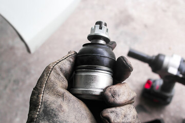 Close up of mechanic hand holding new car lower ball joint replacement part, automotive suspension...