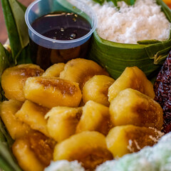 Traditional Indonesian snack called klenyem, made from grated cassava filled with melted palm sugar and deep-fried until golden brown. Indonesian kue basah dessert served on banana leaves