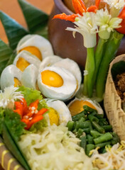 Close-up of traditional Indonesian salted eggs served with vegetables and chili garnish. Authentic Asian cuisine presentation with local ingredients and decorative food arrangement.