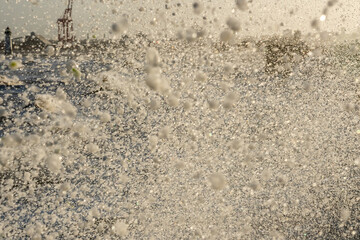 Abstract view of a storm wave crashing at New Brighton with Perch Rock Lighthouse faintly visible through the sea spray in morning light