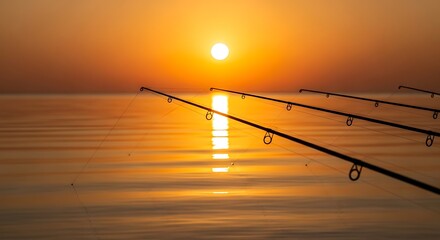 Fishing rods silhouetted against a vibrant orange sunset over a calm body of water, reflecting the suns golden light.
