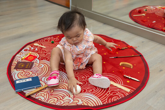 Baby girl choosing future career during chinese one years old birthday celebration, Photographing a little girl&rsquo;s Chinese-style grabbing test on the occasion when she was one year old