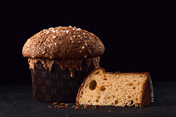 Italian cake panettone, soft traditional sweet bread with nuts, raisins and chocolate on rustic dark background.