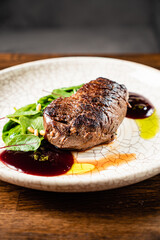 Juicy steak rests on a cracked plate, accompanied by fresh greens and colorful sauces