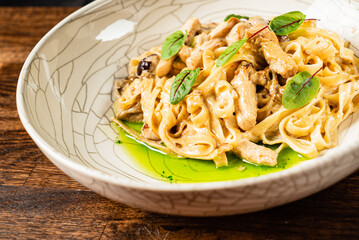 A hearty bowl of pasta featuring savory chicken and herbs, nestled on a wooden table