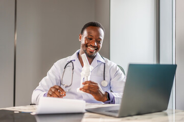 Online medical consultation. African american male orthopedic doctor showing foot skeleton, ankle joint anatomy model explain for patient through talking video call. Physiotherapy treatment, Medical