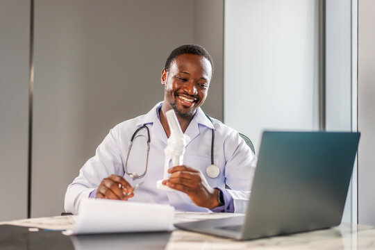 Online medical consultation. African american male orthopedic doctor showing foot skeleton, ankle joint anatomy model explain for patient through talking video call. Physiotherapy treatment, Medical