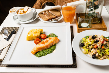 A salmon fillet on a bed of vegetable puree, served with salad and sides